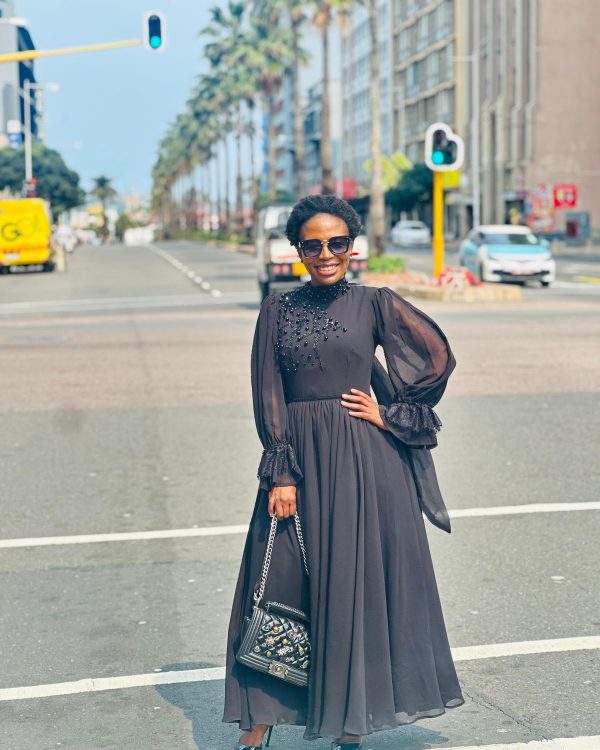 Woman in a black chiffon maxi dress with beaded bodice and sheer ruffle-cuff sleeves