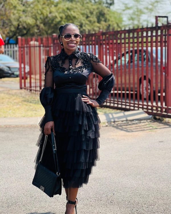 Woman in a black dress with lace bodice, sheer balloon sleeves and tiered tulle skirt