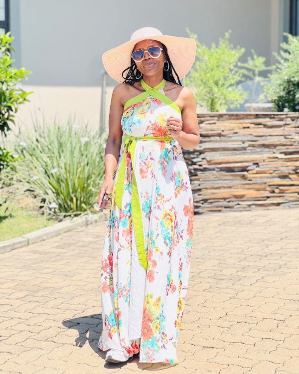 Woman in a white floral halter-neck maxi dress with lime green tie and a wide-brim sun hat
