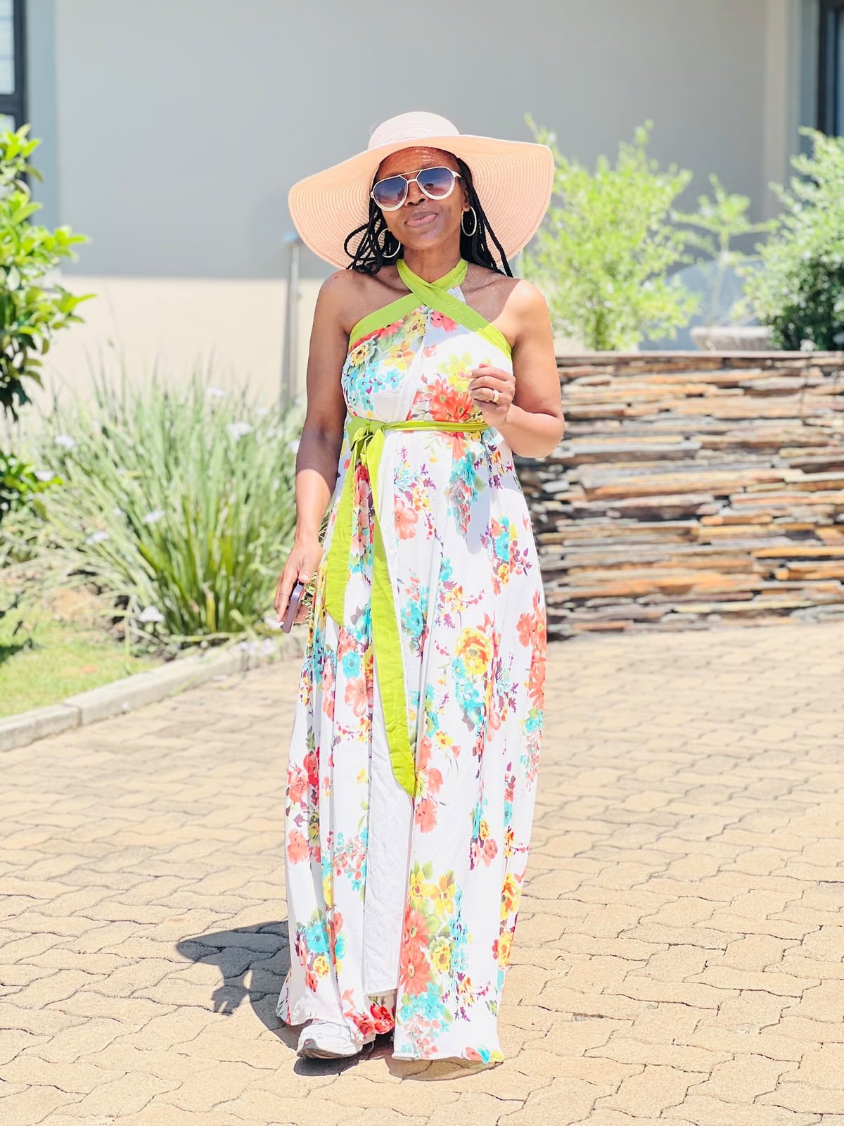 Woman in a white floral halter-neck maxi dress with lime green tie and a wide-brim sun hat