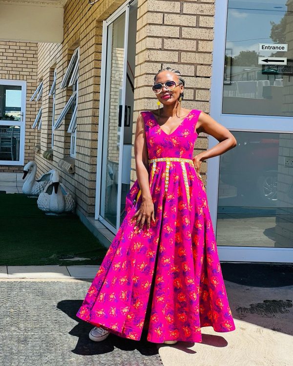 Woman in a pink printed V-neck ball-gown maxi dress with a yellow belt